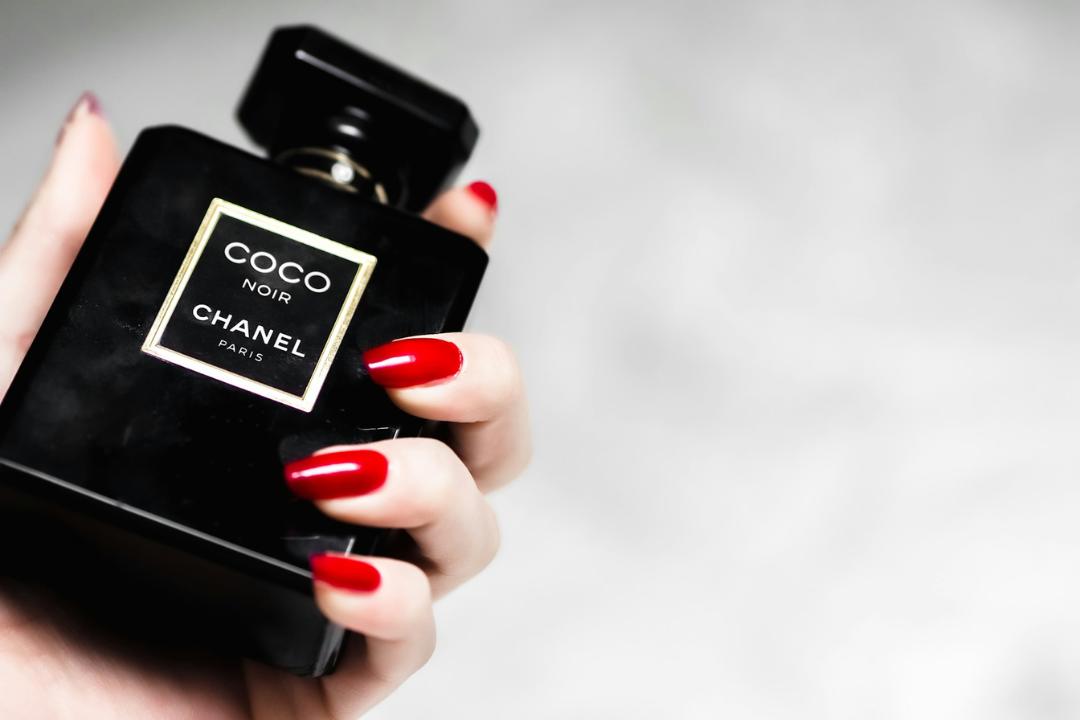 person holding a black and gold Chanel perfume bottle