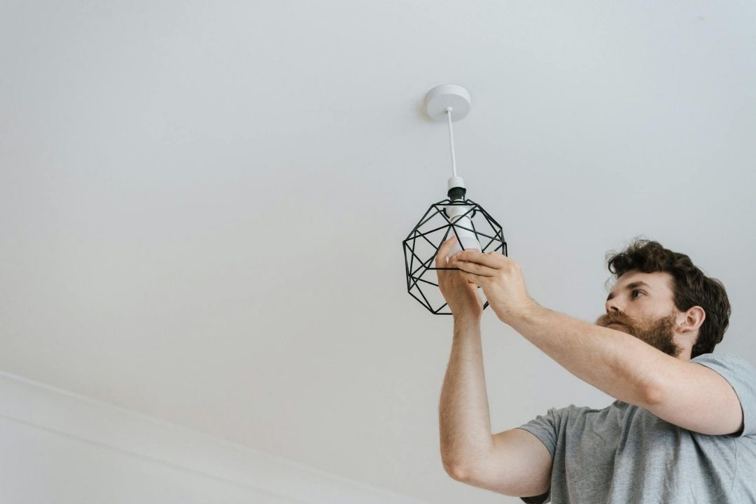 Man screwing light bulb into ceiling light